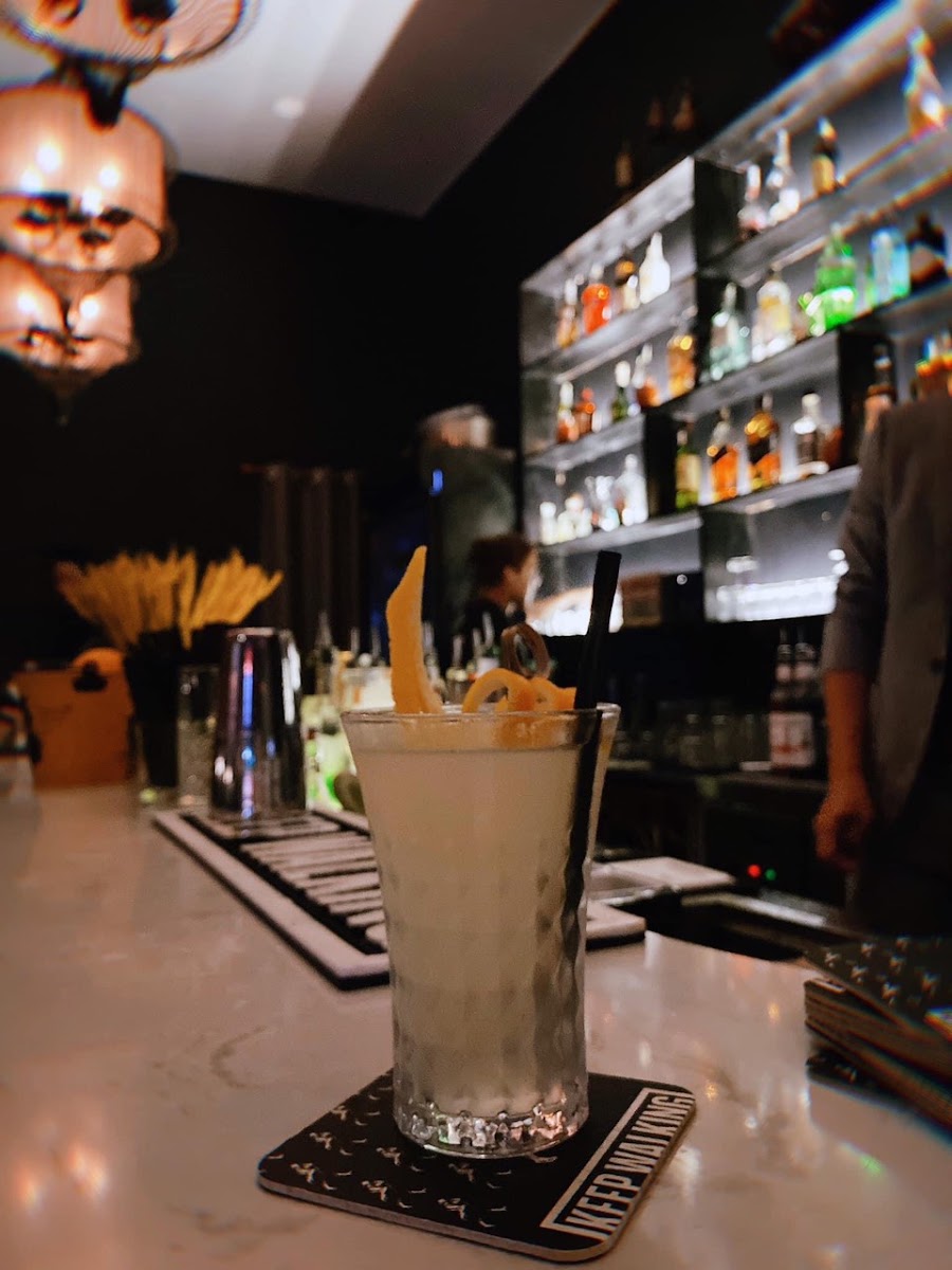 Một ly cocktail sáng màu đặt trên quầy bar tối