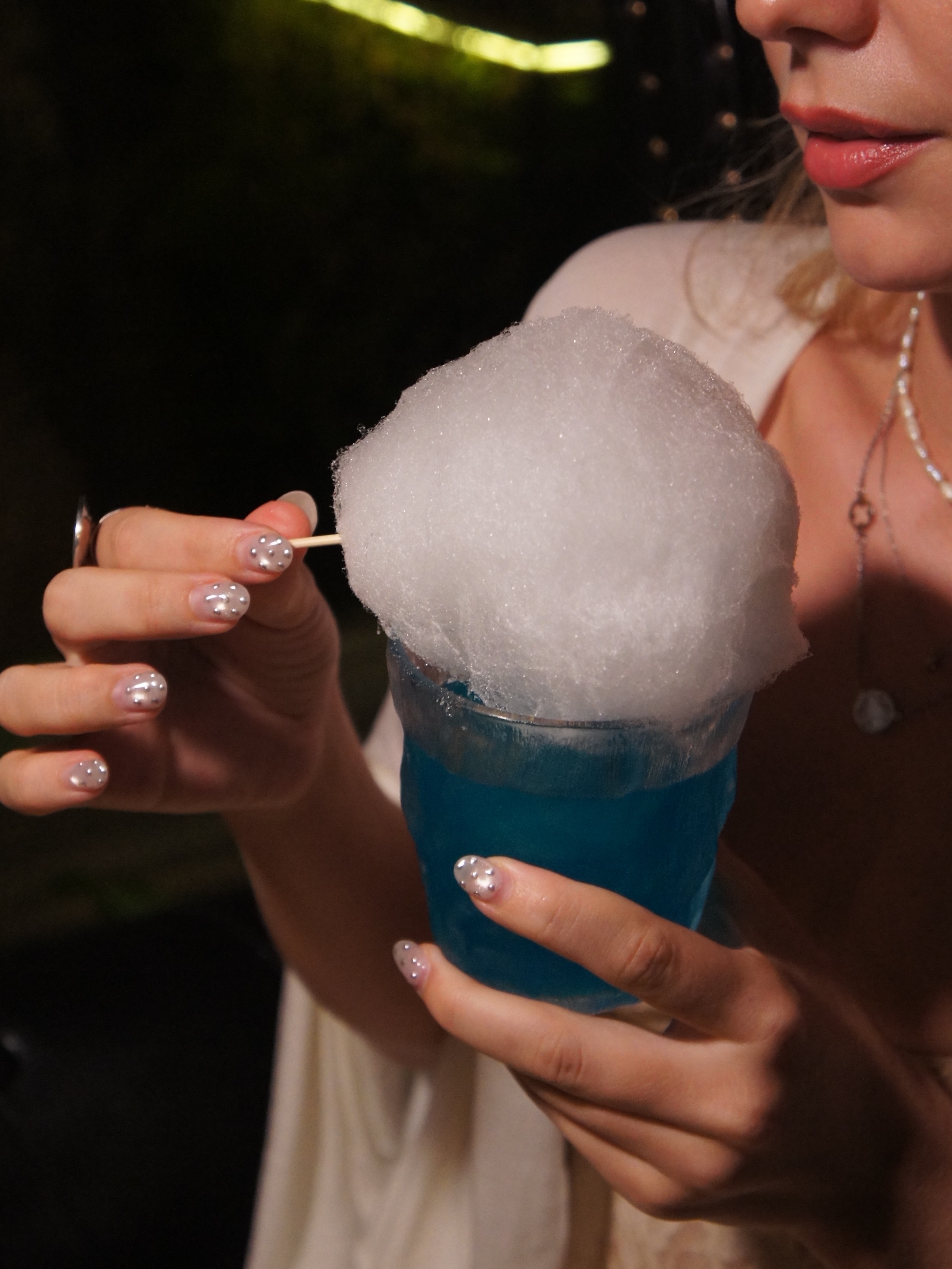Một vị khách cầm ly cocktail xanh phủ lớp bọt trắng lớn